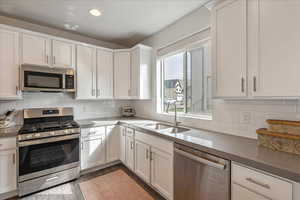 Kitchen featuring stainless steel appliances, white cabinetry, dark stone counters, tasteful backsplash, and recessed lighting