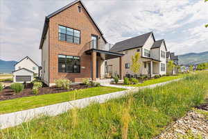 Modern home with brick siding, a residential view, and a mountain view