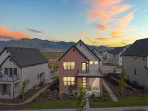Back of property at dusk featuring brick siding, a balcony, a patio, and a residential view