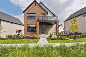 Contemporary home featuring a balcony, stucco siding, and brick siding