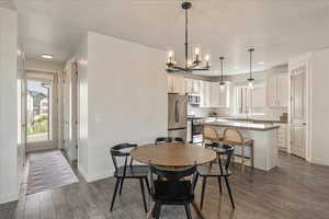 Dining space featuring a chandelier, dark wood finished floors, and plenty of natural light