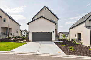 View of front facade featuring a residential view, driveway, and a garage