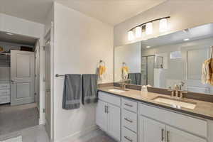 Bathroom with double vanity, a stall shower, and light marble finish flooring