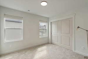 Unfurnished bedroom featuring a closet and light carpet