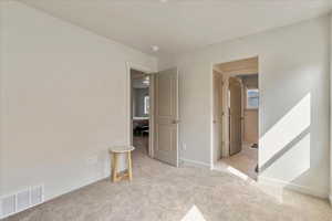 Unfurnished bedroom with light carpet and baseboards