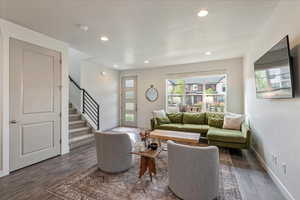 Living room featuring stairway, recessed lighting, dark wood-style floors, and a textured ceiling