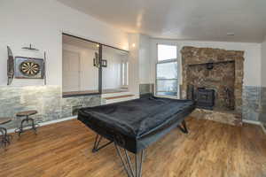 Playroom with billiards, a wood stove, and wood finished floors
