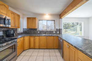 Kitchen with appliances with stainless steel finishes, brown cabinets, backsplash, and plenty of natural light