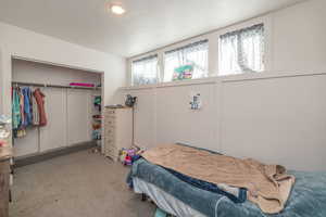 Bedroom with light carpet, a closet, and a textured ceiling
