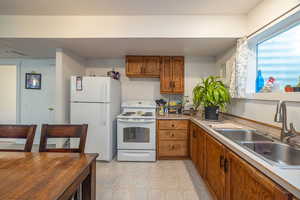 Kitchen with white appliances, brown cabinetry, light countertops, and light flooring