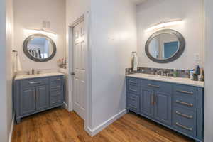 Ensuite bathroom with two vanities, backsplash, and dark wood finished floors