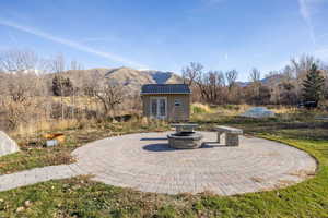 View of patio with a mountain view, an outdoor structure, and an outdoor fire pit
