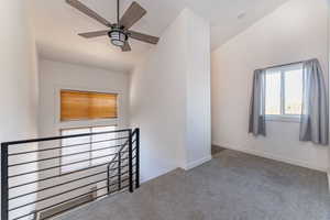 Hallway upstairs lofted ceiling, carpet, and a ceiling fan