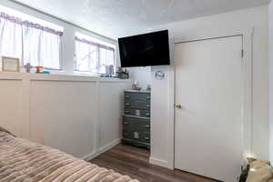 Bedroom featuring dark wood finished floors, a textured ceiling, and a closet