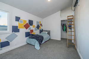 Upstairs Bedroom featuring vaulted ceiling, carpet floors, a wall mounted air conditioner, and a walk in closet