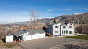 View of front facade featuring an outdoor structure, a shingled roof, a mountain view, driveway, and a detached garage