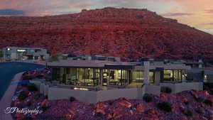 Back of house at dusk featuring a mountain view, stucco siding, and a patio