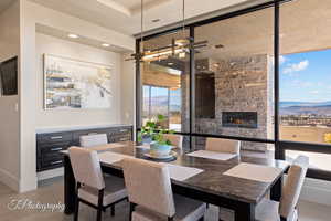 Dining room with a mountain view, a stone fireplace, expansive windows, and recessed lighting