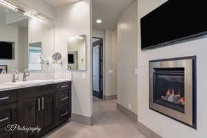 Bathroom with vanity, a glass covered fireplace, light tile patterned flooring, and recessed lighting