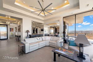 Living area featuring a raised ceiling, a chandelier, a mountain view, a ceiling fan, and recessed lighting