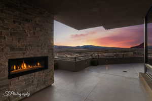 Patio terrace at dusk with a patio area, an outdoor stone fireplace, and a mountain view