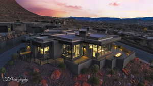 Back of house at dusk with a mountain view, a patio, and stucco siding