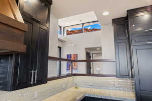 Kitchen with open shelves, recessed lighting, light stone countertops, and dark cabinets