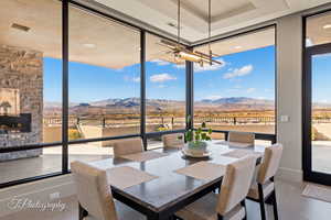 Dining space featuring a wall of windows, a mountain view, healthy amount of natural light, a stone fireplace, and recessed lighting