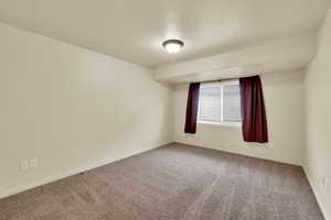 Carpeted empty room with a textured ceiling and baseboards