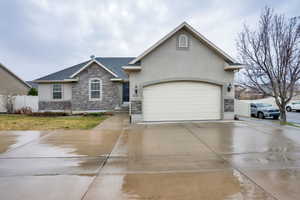 View of front of property featuring stone siding, stucco siding, driveway, and roof with shingles