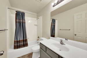 Bathroom featuring shower / tub combo with curtain, vanity, and dark tile patterned floors