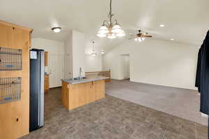 Kitchen featuring lofted ceiling, dark colored carpet, freestanding refrigerator, a chandelier, and hanging light fixtures