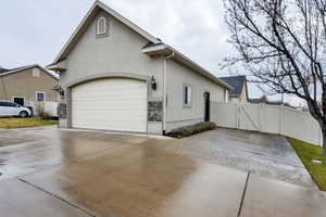 View of property exterior featuring concrete driveway, stucco siding, a gate, and a garage