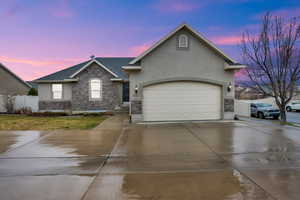 View of front of property featuring stone siding, stucco siding, and concrete driveway