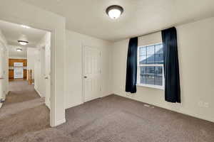 Unfurnished bedroom featuring light carpet and a textured ceiling