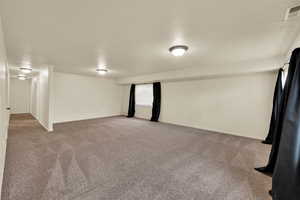 Basement with a textured ceiling and light colored carpet