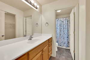 Full bathroom with vanity, a shower with shower curtain, and a spacious closet