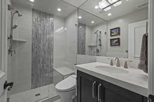 Bathroom with vanity, a stall shower, tile walls, and recessed lighting