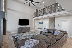 Living room featuring ornamental molding, a towering ceiling, light wood finished floors, recessed lighting, and a ceiling fan