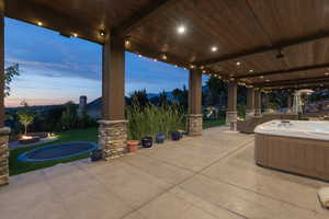 Patio terrace at dusk with a hot tub, a patio area, and an outdoor fire pit