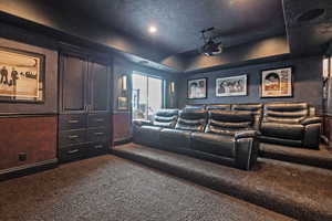 Cinema room with dark carpet, a textured ceiling, and a tray ceiling