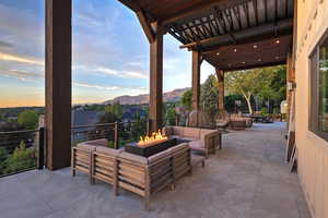Patio terrace at dusk featuring a patio area, a mountain view, and an outdoor living space with a fire pit