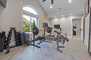 Exercise area with light wood-type flooring, high vaulted ceiling, a ceiling fan, and recessed lighting