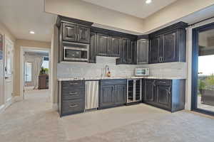 Kitchen with plenty of natural light, light colored carpet, beverage cooler, and recessed lighting
