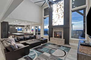 Living area with a high ceiling, a fireplace, light wood-type flooring, and recessed lighting