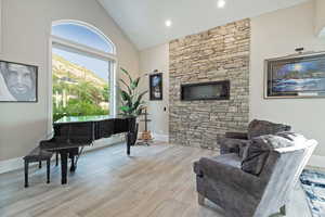 Sitting room with wood finished floors, high vaulted ceiling, and a fireplace