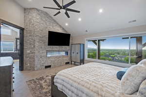 Bedroom with high vaulted ceiling, a stone fireplace, multiple windows, light wood-style flooring, and recessed lighting