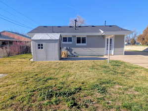 Back of house featuring a shed, a shingled roof, and a patio area