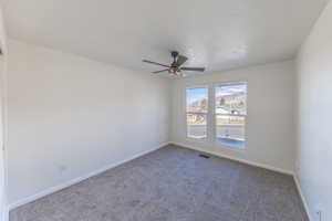 Carpeted empty room with baseboards and a ceiling fan