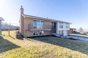 Front view of property with brick siding, a chimney, an attached garage, and a lawn